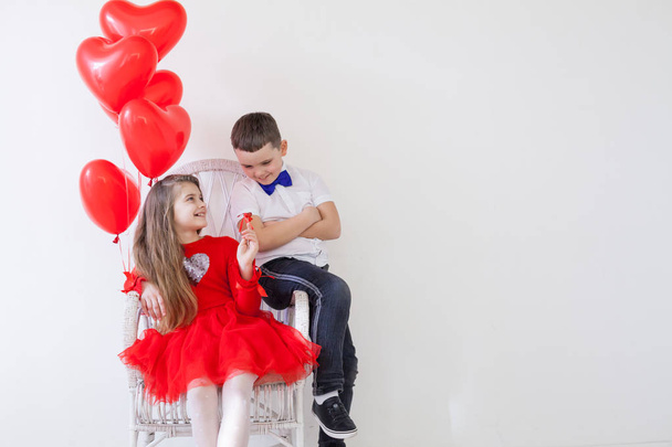 女の子と男の子は赤い心の風船で座っている - 写真・画像