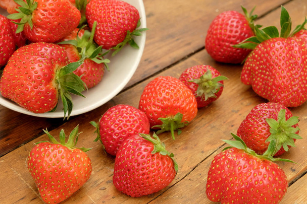 strawberries in a bowl and on a wooden table top - Photo, Image