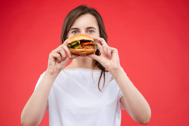Medium close-up portrait of beautiful young fashion woman biting fresh appetizing sandwich - Fotografie, Obrázek