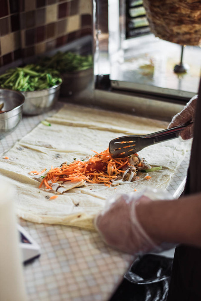 Kokkaan fajitoja kahvilassa. Kokkaan shawarmaa pitassa keittiössä. Kääri kana, porkkanat, tomaatti pitaleipään
. - Valokuva, kuva