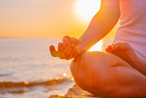 Femme pratique le yoga assis dans la pose Lotus au lever du soleil. Silhouette de femme méditant au coucher du soleil sur la plage
 - Photo, image