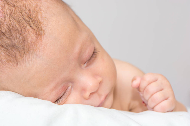 Портрет новорожденного мальчика, лежащего на белых простынях
 - Фото, изображение