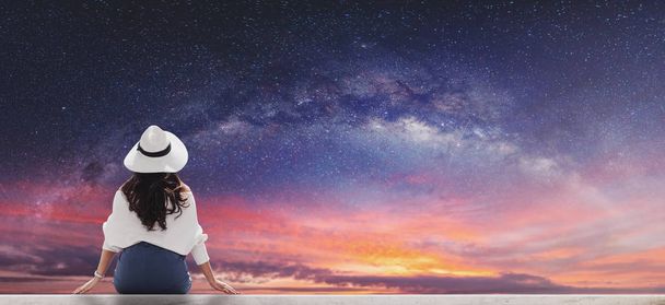 Молода жінка в білому капелюсі і тканині дивиться на красиве зоряне небо з молочним способом на світанку
 - Фото, зображення