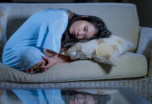 młody piękny smutny i przygnębiony Asian japoński kobieta w domu sofa kanapa uczucie ogarnia cierpienie lęk kryzys i depresja problem płacz  - Zdjęcie, obraz