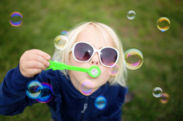 Niña soplando burbujas afuera en un día de verano
 - Foto, imagen