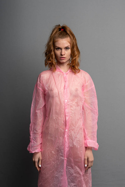 young beautiful girl posing in the studio, standing in a pink raincoat - Foto, Bild