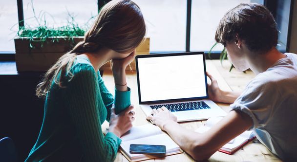 Skilled man and woman working togetherness on laptop device with mock up area for your internet advertising, smart hipsters reading news on university website searching schedule during e learning - Photo, image