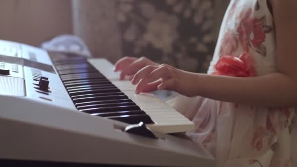 Tanınmayan küçük kız elektrikli piyano çalmak için okuyor. - Video, Çekim