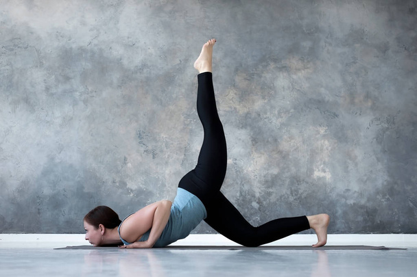Vrouw beoefenen van yoga doen Eka Pada Shalabhasana, de sprinkhaan pose variatie - Foto, afbeelding