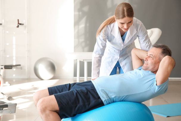 Physiotherapist working with mature patient in rehabilitation center - Fotografie, Obrázek