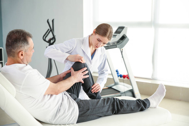Physiotherapist working with mature patient in rehabilitation center - Foto, imagen