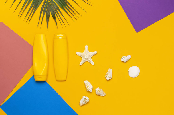 Yellow bottles of sunscreen cream, tropical palm leaves, shells, starfish on colorful background top view flat lay copy space. Sun protection. Summer background, vacation, travel concept - Fotografie, Obrázek