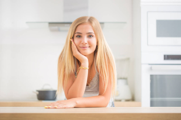 Young cheerful blonde girl in the house kitchen. She thinks what - Fotografie, Obrázek