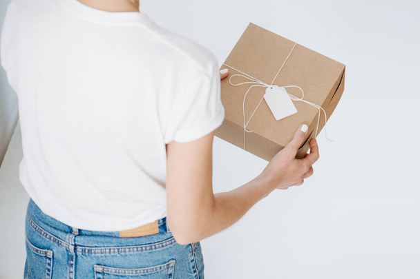 Woman in casual clothes holding postal cardboard box, checking wrappings at home - Photo, image