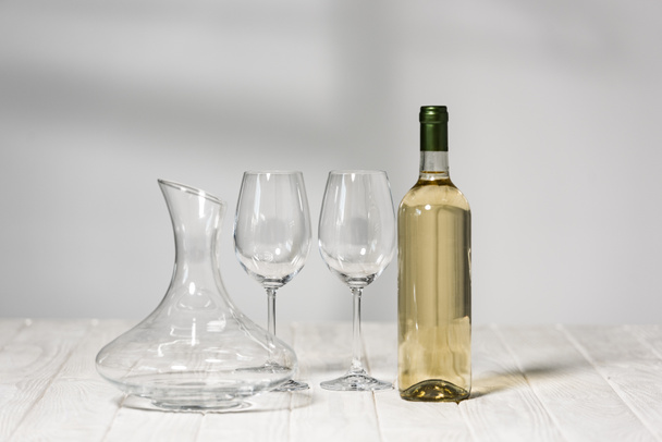 empty wine glasses, bottle of wine and jug on wooden surface in restaurant - Fotó, kép