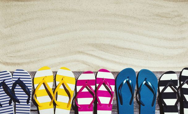Conjunto de chinelos coloridos no deck de praia
 - Foto, Imagem