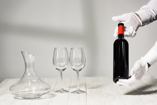 cropped view of waiter in white gloves holding bottle of wine - Photo, image