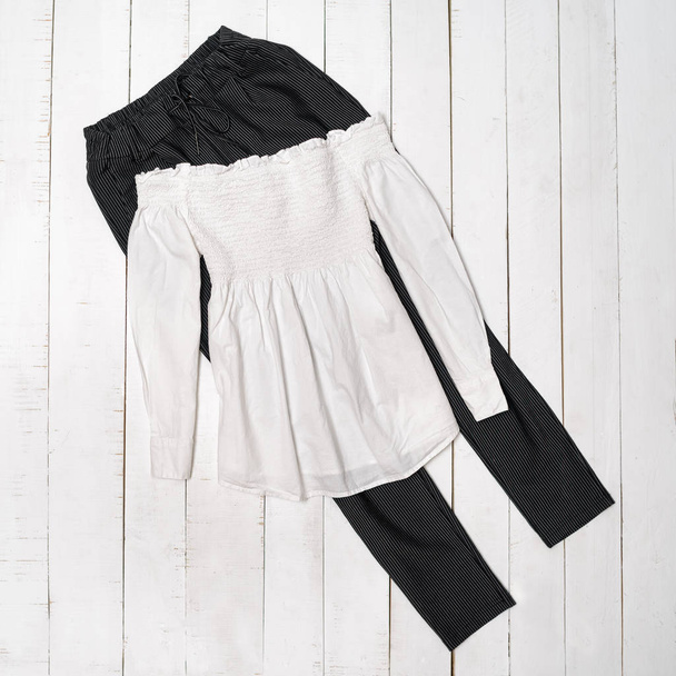 Blouse blanche sur pantalon noir. Fond en bois. Concept tendance
 - Photo, image