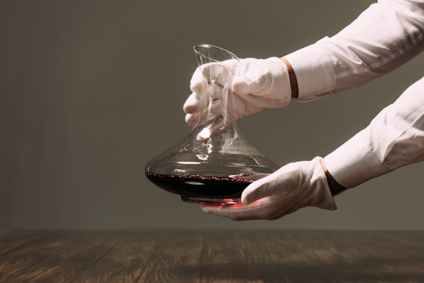 partial view of waiter in white gloves holding jug of wine in restaurant - Fotografie, Obrázek