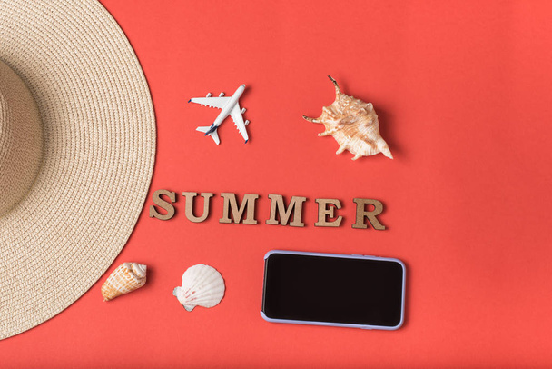 Z dřevěných dopisů slovo léto. Mušle, část kloboučku, malé letadlo a smartphone, živé korálové pozadí. Rovně ležet. Koncepce cestování - Fotografie, Obrázek