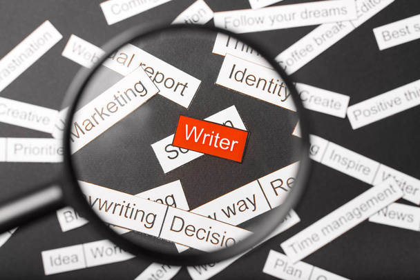 Magnifier glass over the red inscription writer cut out of paper. Surrounded by other inscriptions on a dark background. Word cloud concept. - Foto, Imagem