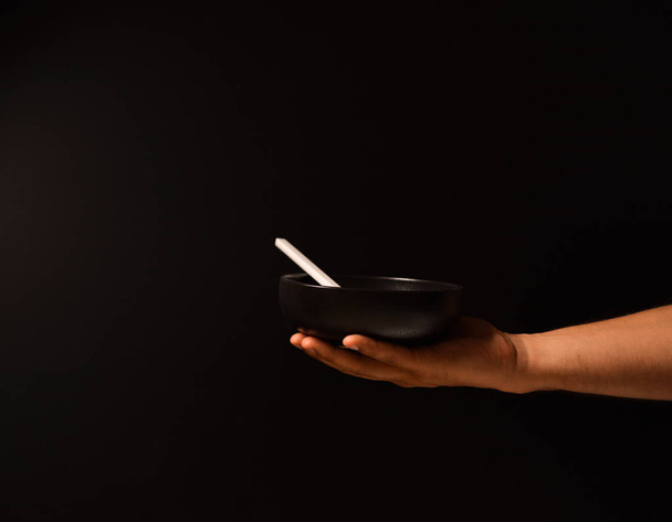 Man's hand on a black background with a plate of food - Valokuva, kuva