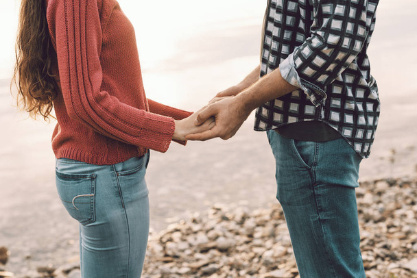 Süßes junges Paar hält Händchen am See - Foto, Bild