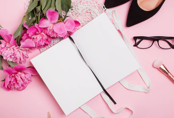 Open notepad mock-up on the table with feminine accessories and pink peonies - Фото, изображение