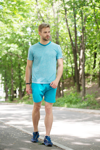 Outdoor sport training. Handsome man in sport wear walking on natural landscape. Athletic sportsman practising sport activities on summer day. Sport and fitness - Foto, imagen