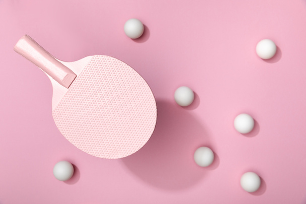 top view of white table tennis balls scattered under racket on pink background - Foto, Imagem