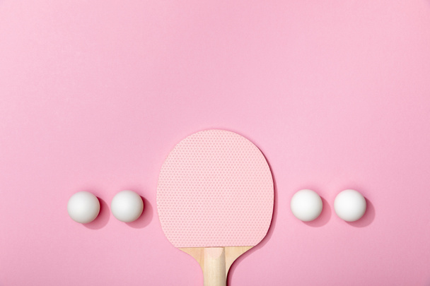 flat lay with white table tennis balls and wooden racket on pink background - Foto, afbeelding