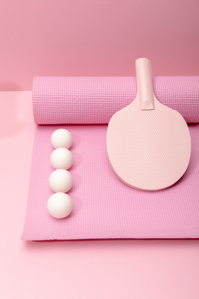 tendido plano con pelotas blancas de ping-pong y raqueta en la colchoneta de fitness sobre fondo rosa
 - Foto, Imagen