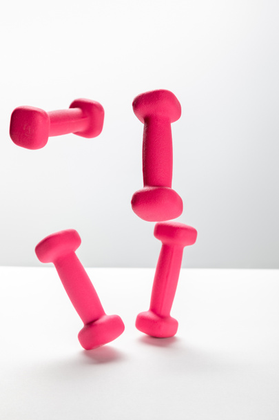 pink bright dumbbells flying in air on white background - Foto, Bild