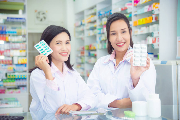 Deux asiatique femme pharmacien tenant la médecine et sourire
 - Photo, image