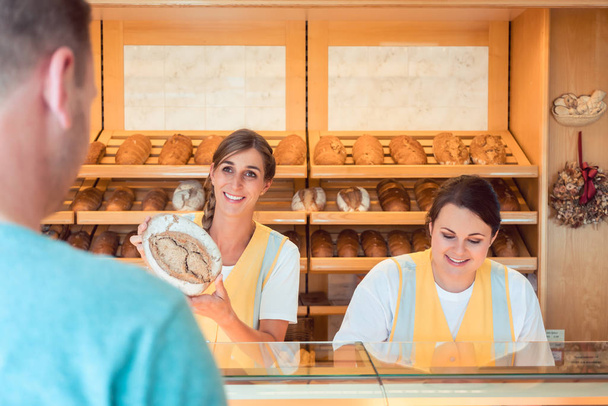 Twee salesladies verkoop van brood en andere producten in bakkerij winkel - Foto, afbeelding