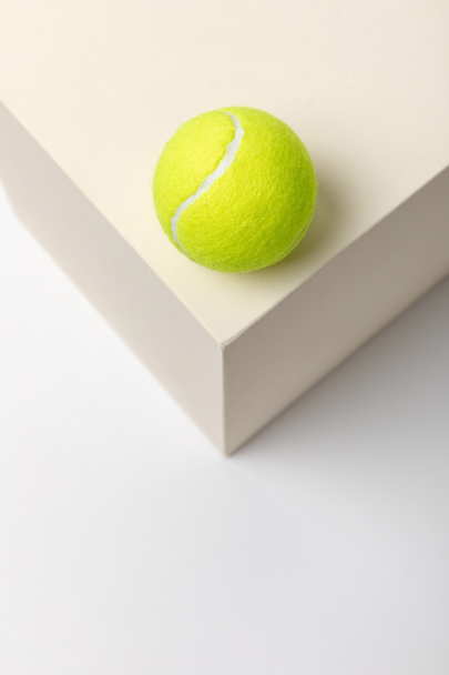 ярко-желтый теннисный мяч на кубе на белом фоне
 - Фото, изображение