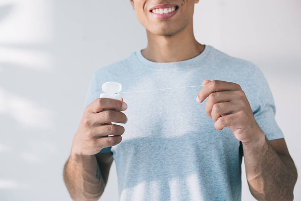 cropped view of man holding dental floss while standing in sunlight  - Zdjęcie, obraz