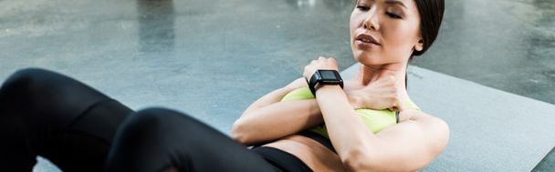 Panoramaaufnahme einer jungen Frau mit geschlossenen Augen beim Bauchmuskeltraining auf einer Fitnessmatte  - Foto, Bild