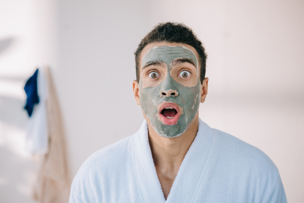 shocked man with clay mask on face looking at camera - Fotó, kép