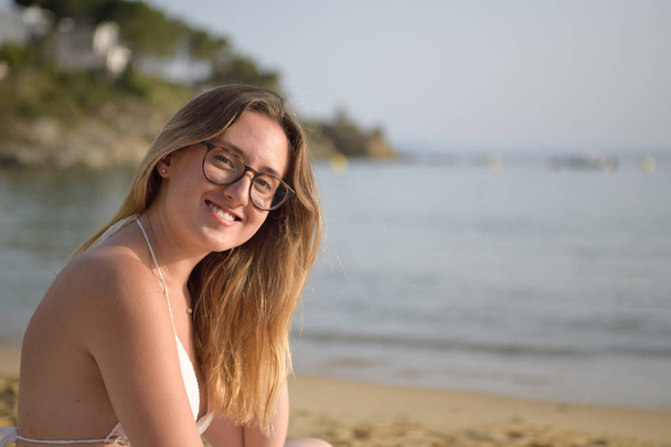 Mladá šťastná žena se dívá na kameru na pláž - Fotografie, Obrázek