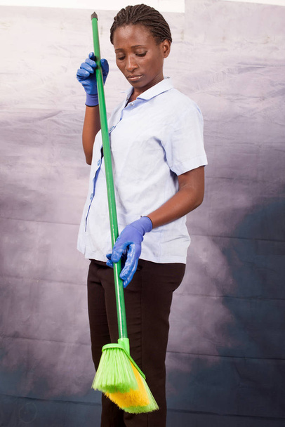 Young smiling housewife with blue gloves and broom - Фото, зображення