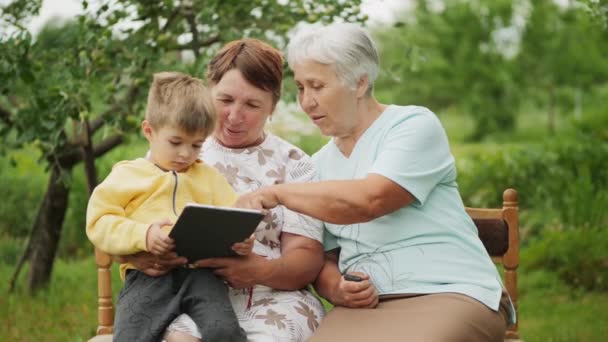 Dos abuelas y nieto jugando juegos en la tableta
 - Metraje, vídeo
