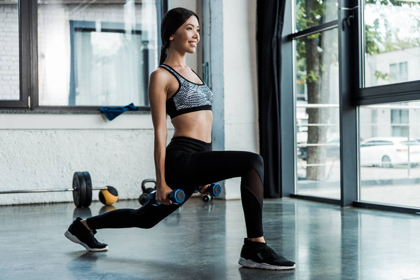 felice sportswoman facendo esercizio squat con manubri
  - Foto, immagini