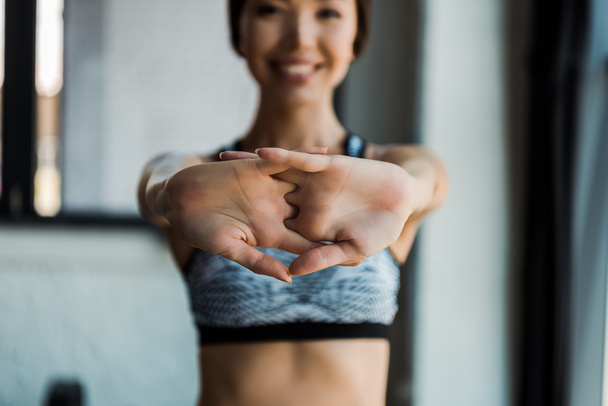 selektiver Fokus des glücklichen Mädchens Stretching beim Aufwärmen im Fitnessstudio   - Foto, Bild