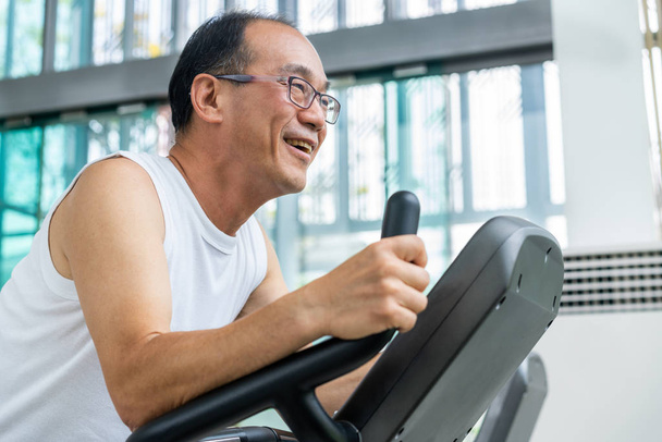 Senior man oefening op loopband in fitnesscentrum - Foto, afbeelding