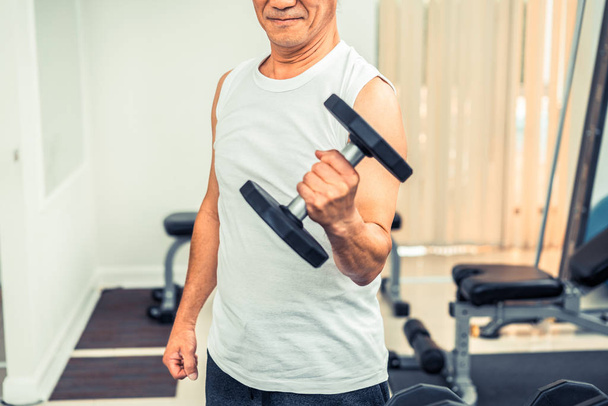 Starszy mężczyzna podnoszenie hantle w siłowni fitness. - Zdjęcie, obraz