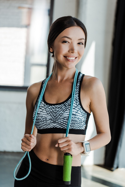happy young woman smiling while holding jumping rope  - Photo, Image