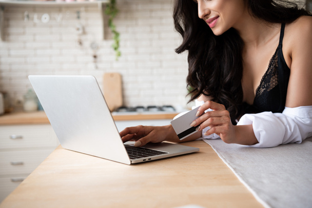 cropped view of sexy girl in black underwear and white shirt using laptop and holding credit card - Foto, immagini