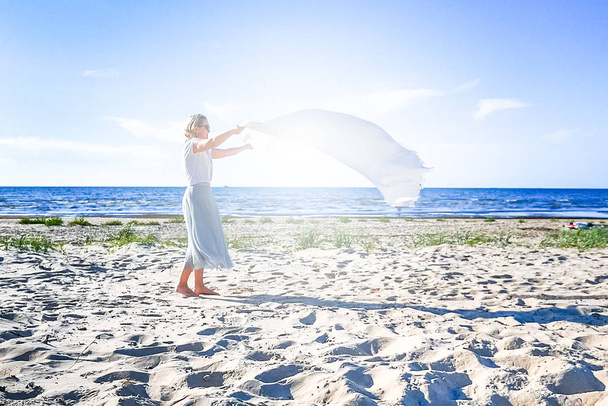 Deniz plajında beyaz sallanan battaniye ile kadın - Fotoğraf, Görsel
