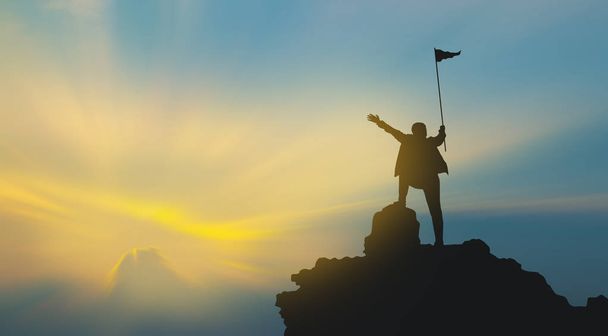 silhouet van de mens op bergtop boven hemel en zon licht achtergrond, business, succes, leiderschap, prestatie en mensen concept - Foto, afbeelding